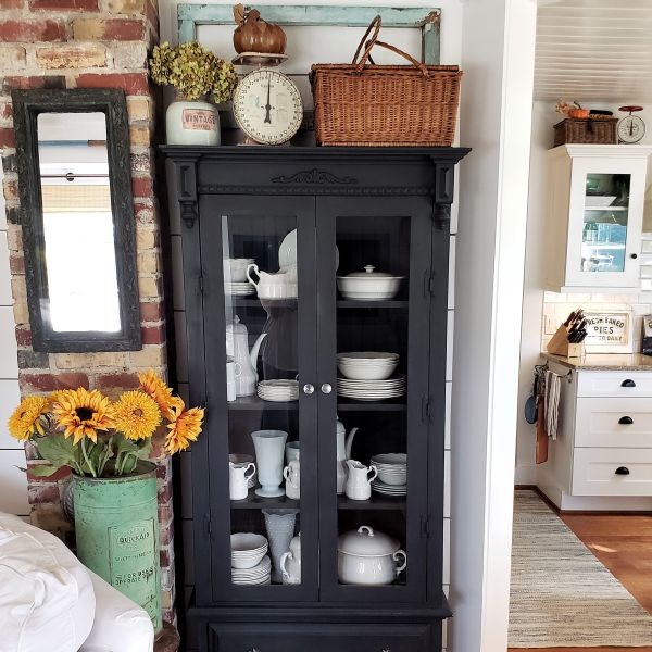 Black glass cabinet with white ironstone and sunflowers