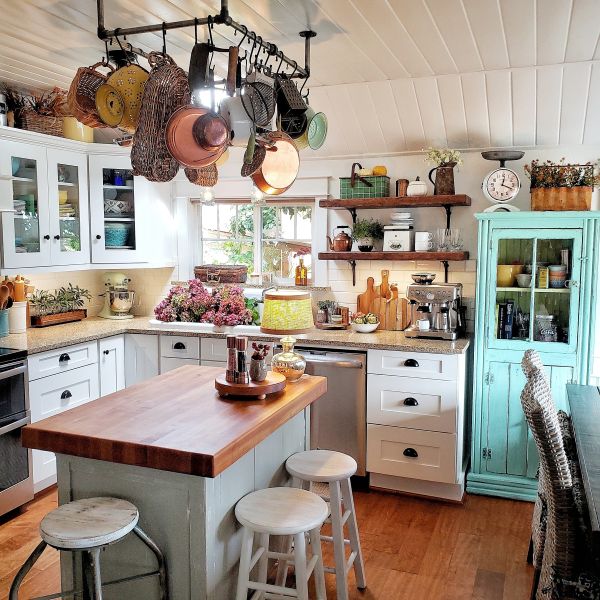 Pot rack, butcher block island, turquoise glass cabinet in kitchen