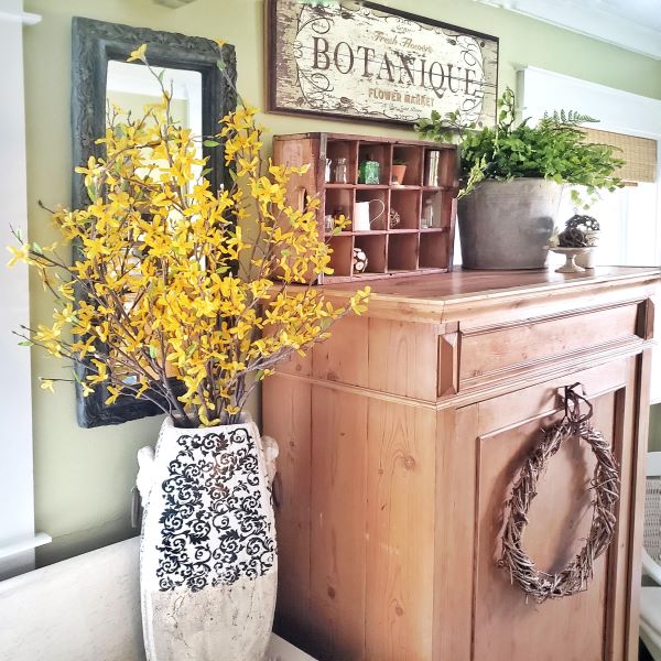 faux forsythia flowers and pine cabinet