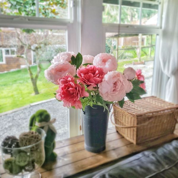 faux peony flowers in front of a window