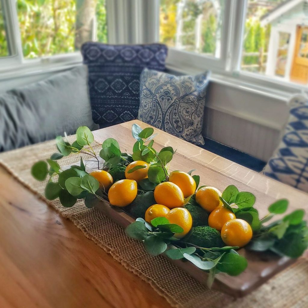 Dough bowl filled with lemons and moss decorative balls for spring.