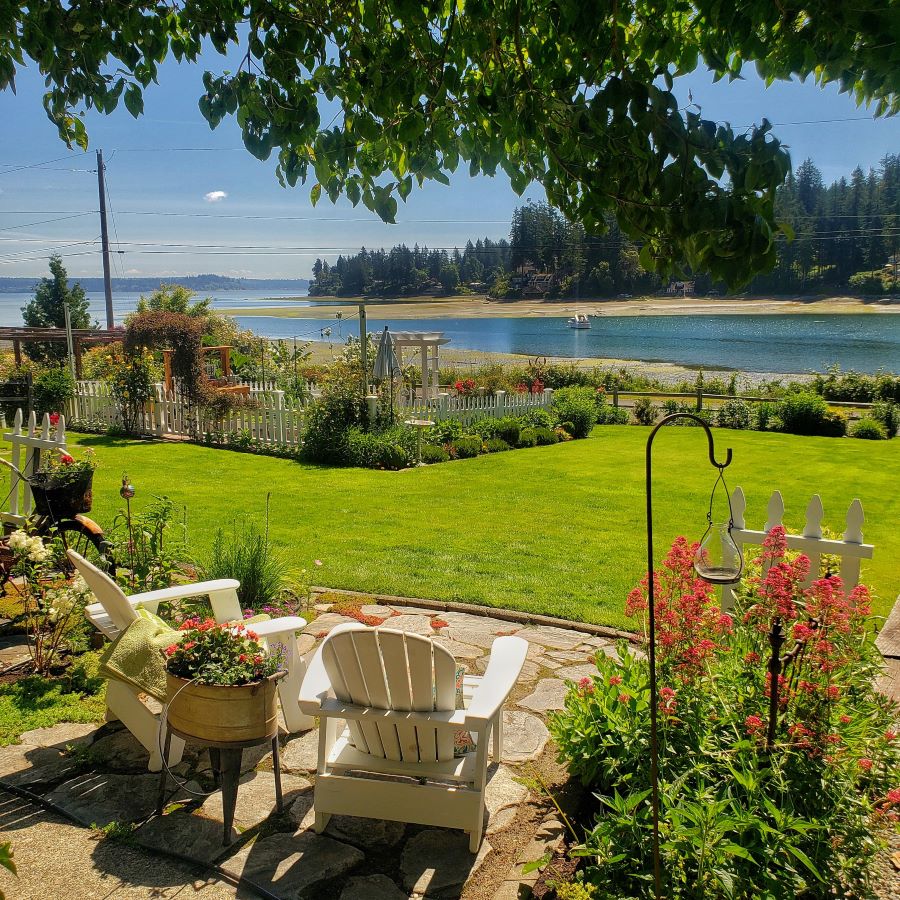 my cottage garden summer view with 2 Adirondack chairs overlooking a green lawn and the Puget Sound