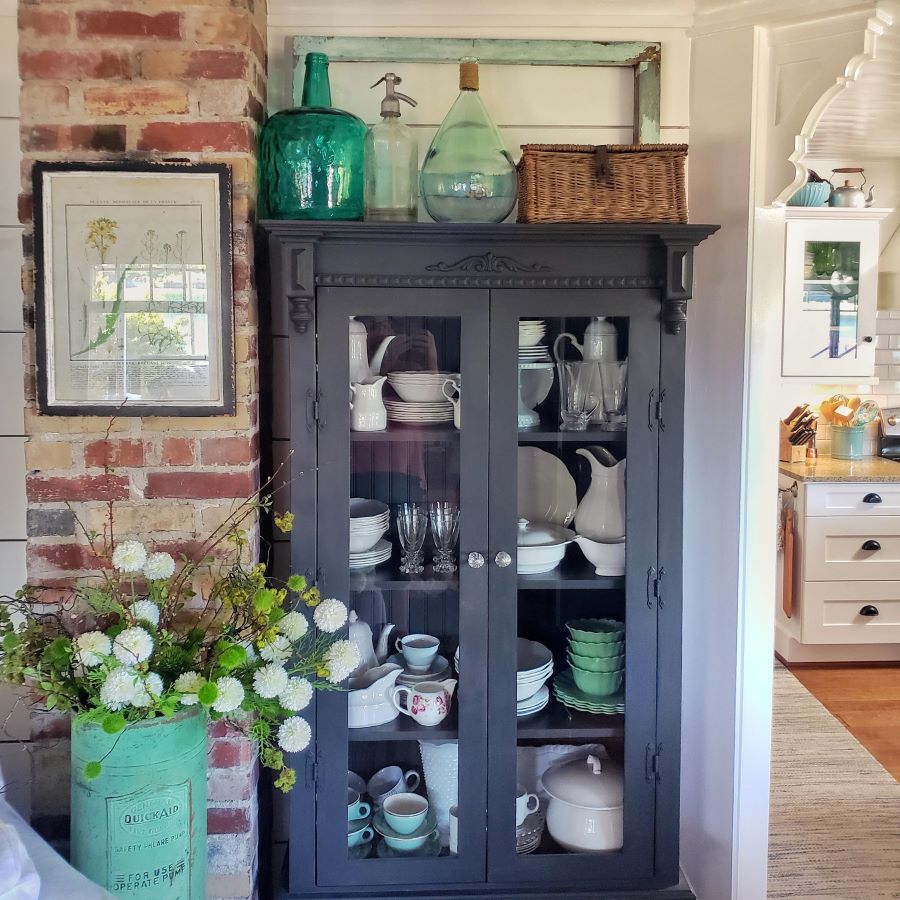 black glass cabinet  with ironstone and green and blue decor