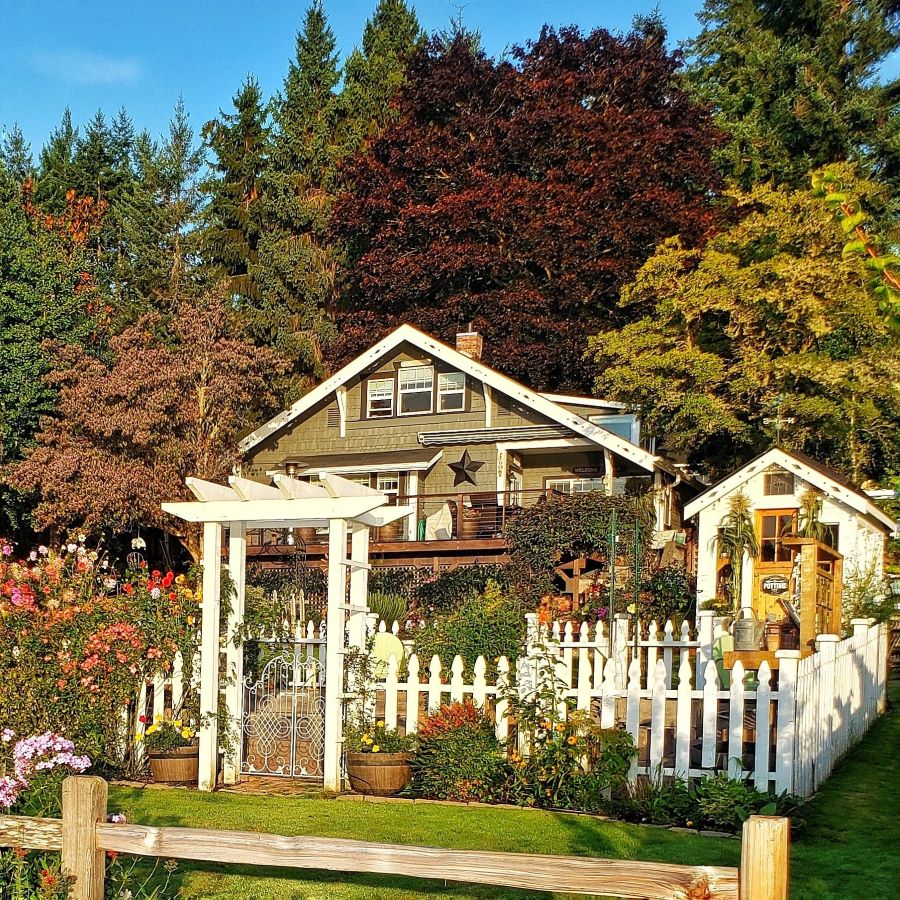 view of cottage and greenhouse with white picket fence