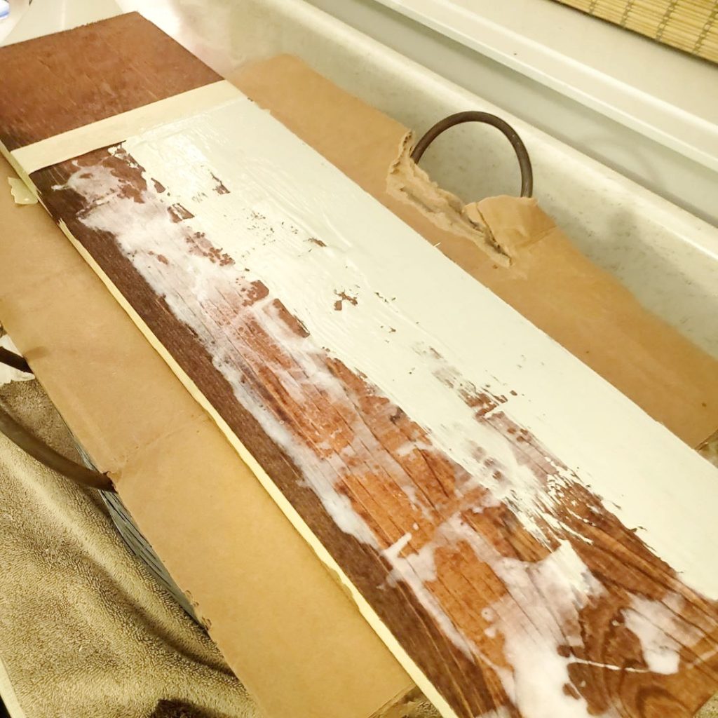 adding white paint to a wood board
