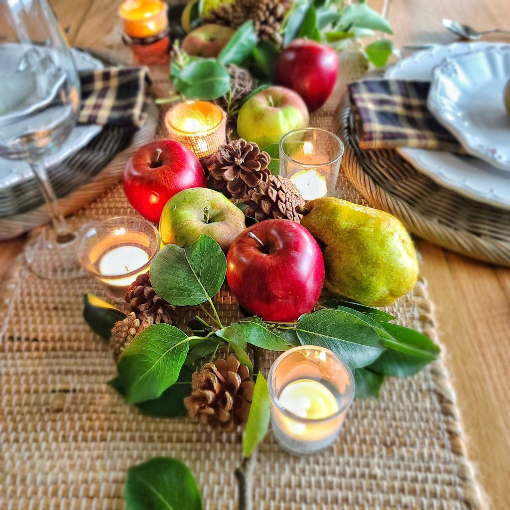cozy fall kitchen decor: red apples, pears, pine cones, and tealight candles
