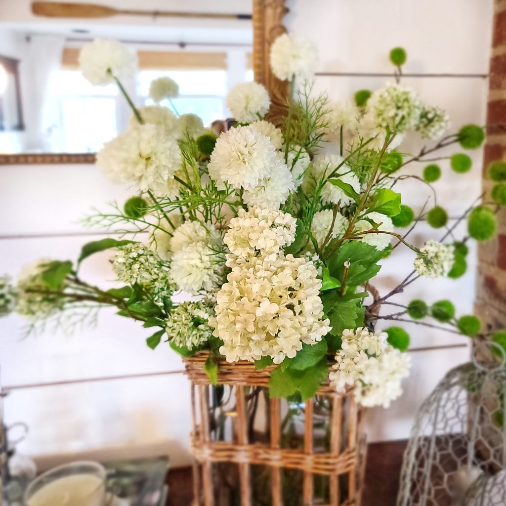 white faux flowers and rattan vase