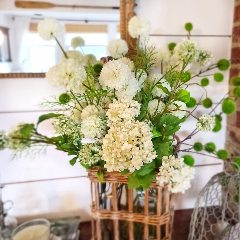 faux white hydrangeas in wicker and glass vase