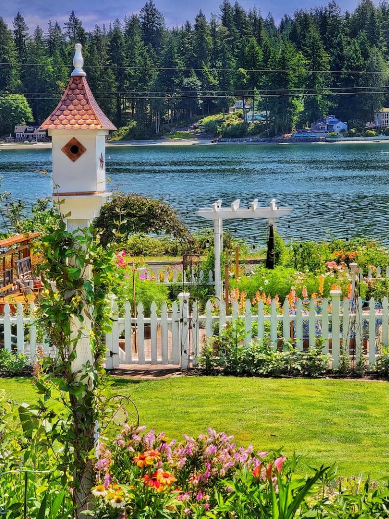 Birdhouse and picket fence cutting garden in early summer cottage garden