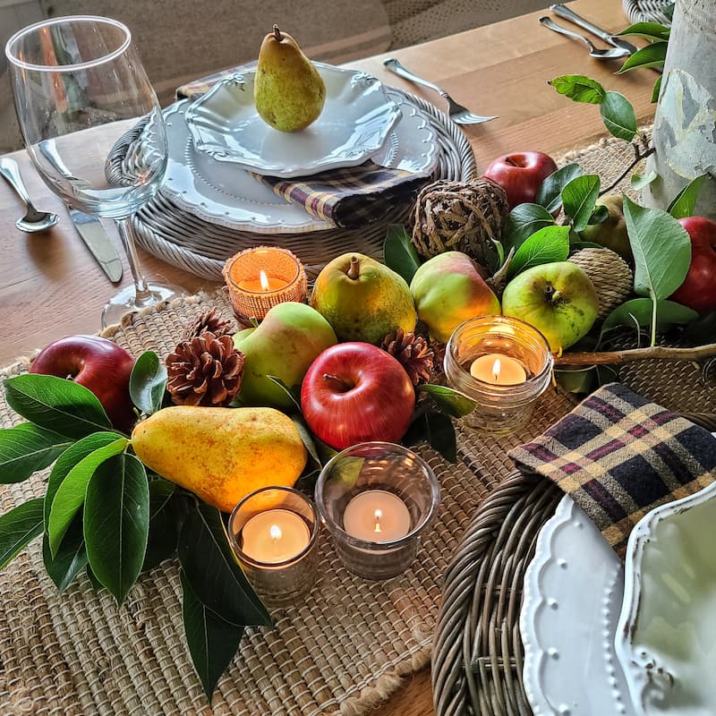 apples, pears, pinecones and candles on fall table