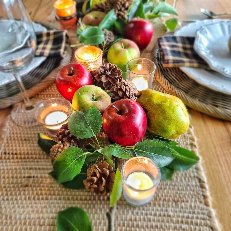 red apples and green pears with pinecones and tealights for fall centerpiece