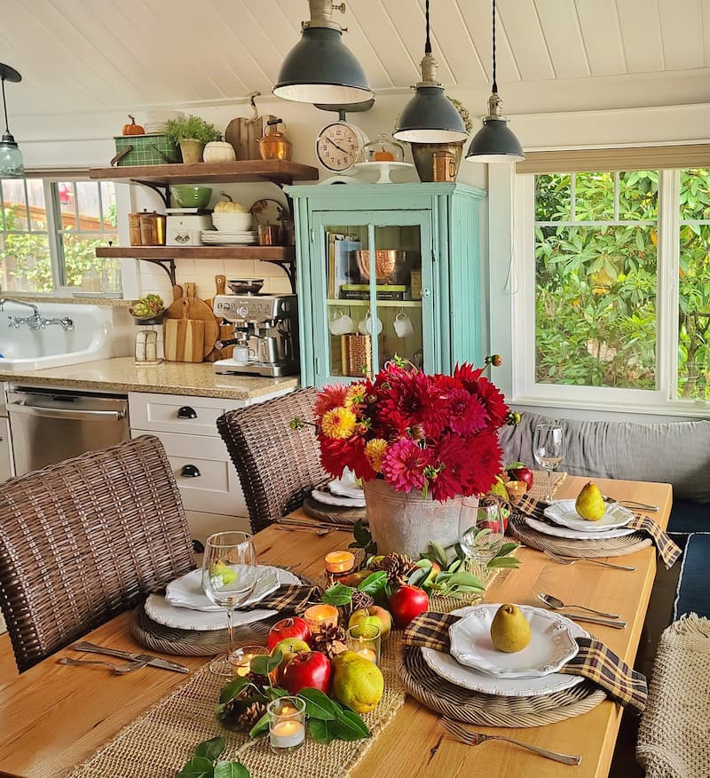 fall tablescape with galvanized bucket of red and fuchsia dahlias and apples and pears for centerpiece