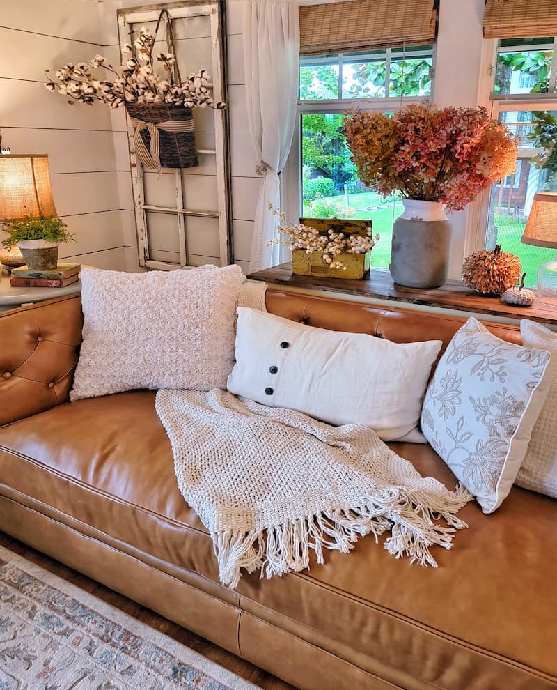 Transition Your Home Decor From Summer To Fall: leather couch with neutral colored pillows and throws