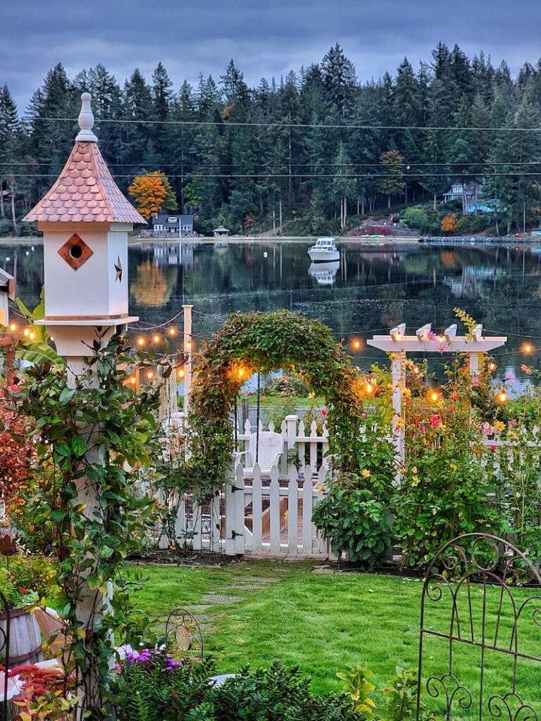 white picket fence garden and birdhouse with water view