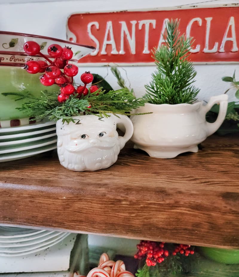 Santa mug with greenery and berries on shelf