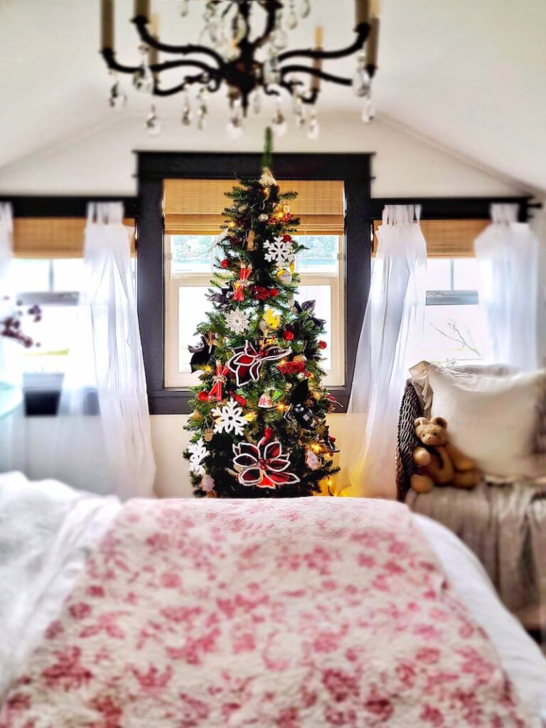 Christmas decor theme: Christmas tree with white snowflakes and red and black plaid poinsettias in bedroom