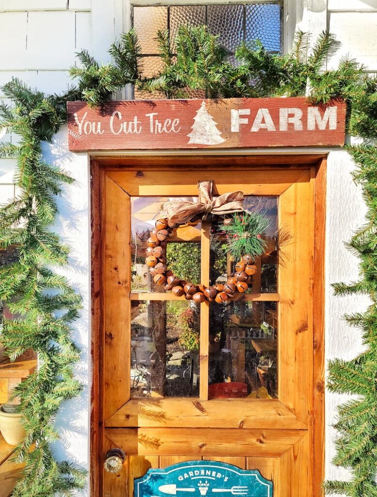 garland and rustic bell wreath hanging on front porch door