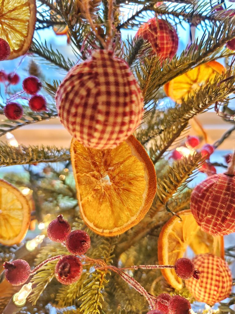 dried orange slices with checked ornaments and berries on tree
