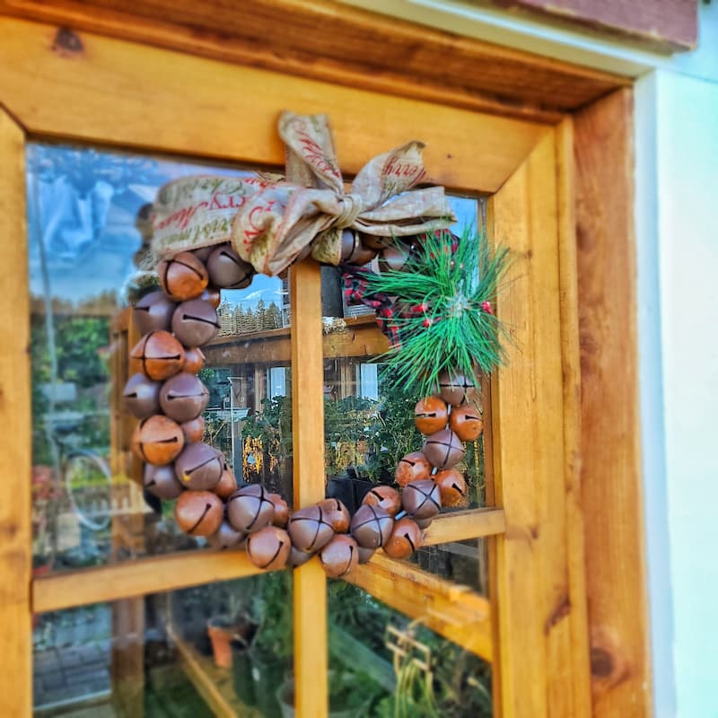 rustic bell wreath hanging on front porch door