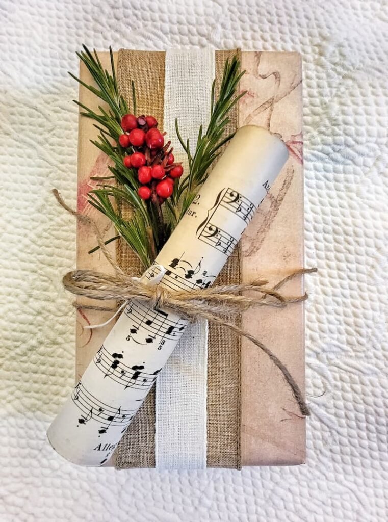 wrapped Christmas gift with greenery, red berries and sheet music