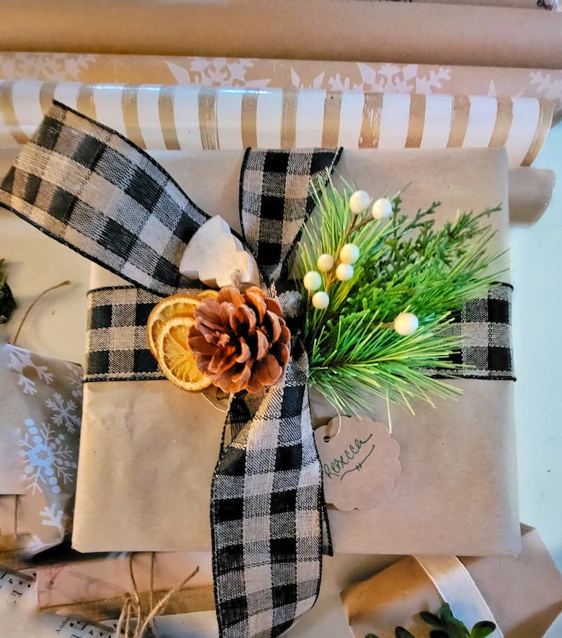 wrapped Christmas gift with black plaid ribbon and natural elements