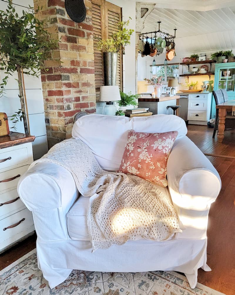 white slipcovered chair with rose pillow and cream throw