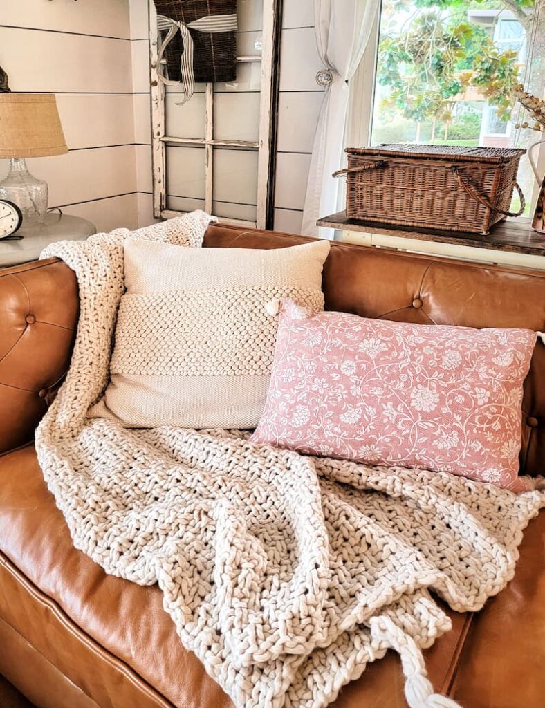 rose colored pillow and cream accessories on leather couch