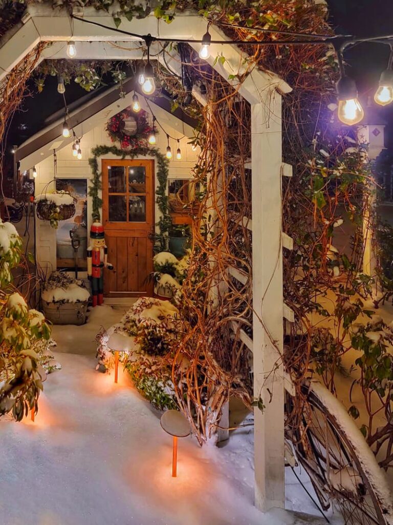 Christmas decor in front of greenhouse and snow on the pathway