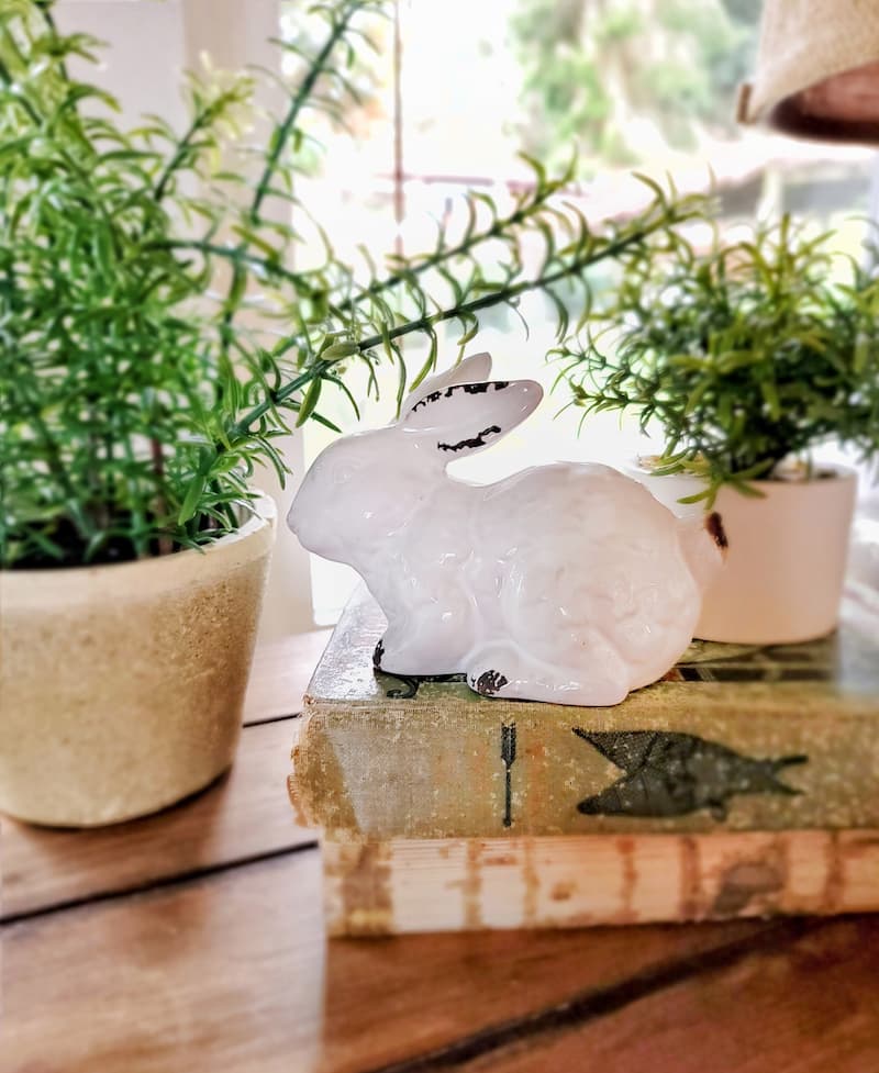 white ceramic bunny with greenery and vintage books Easter vignette tabletop ideas