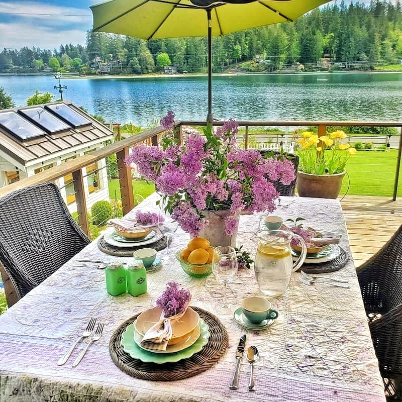 An outdoor spring tablescape out on the deck, with lilacs and over looking the bay