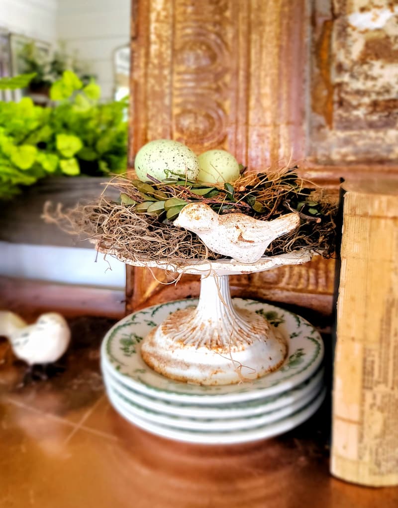 decorative birdbath with nest and eggs on green and white vintage plates