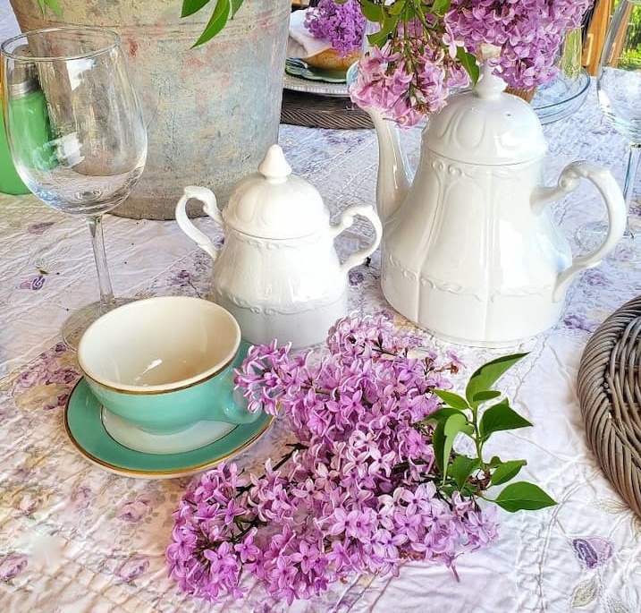 ironstone tea pots and vintage cup and saucer with lilacs on the table