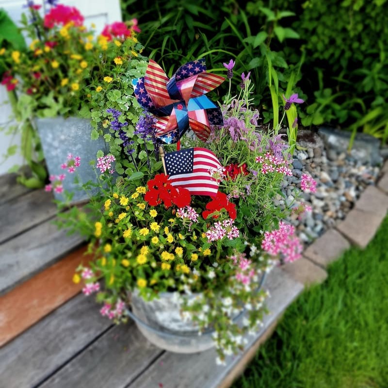 container of flwoers with patriotic pinwheels and flags