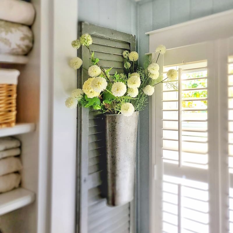 faux flowers in hanging container on shutters