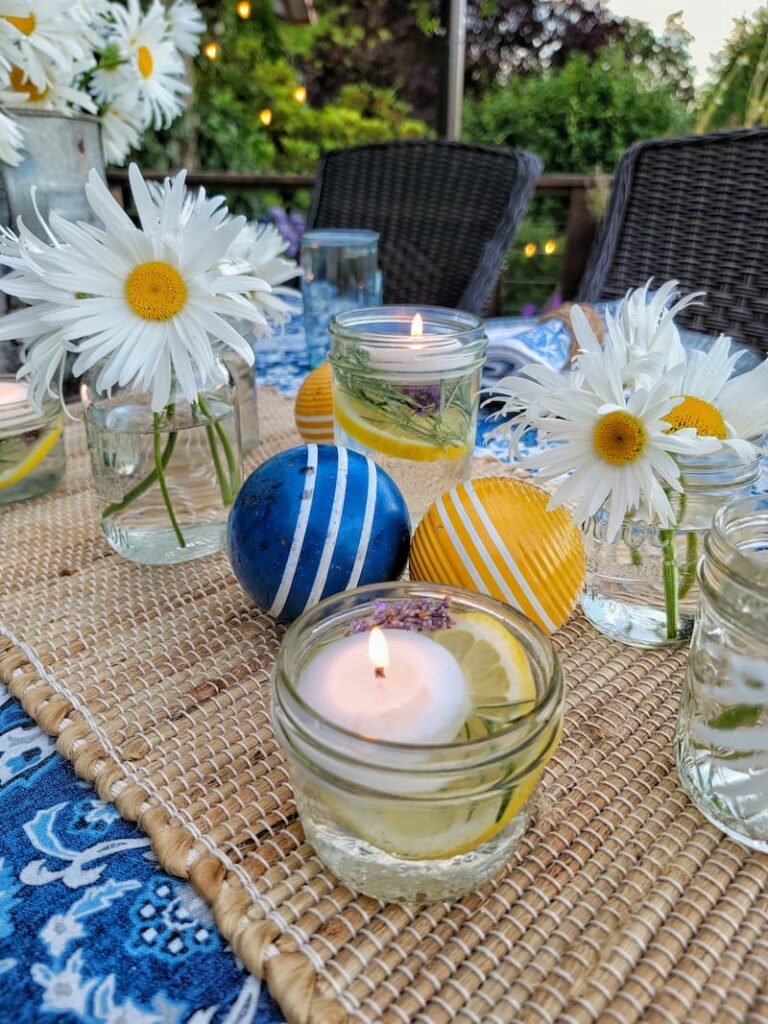 Summer tablescape ideas:  centerpiece with yellow and blue croquet balls, daisies, and floating candles