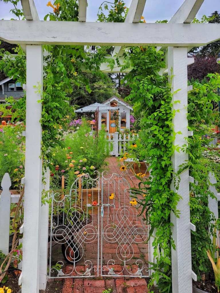 garden path with gate and brick pathway to greenhouse