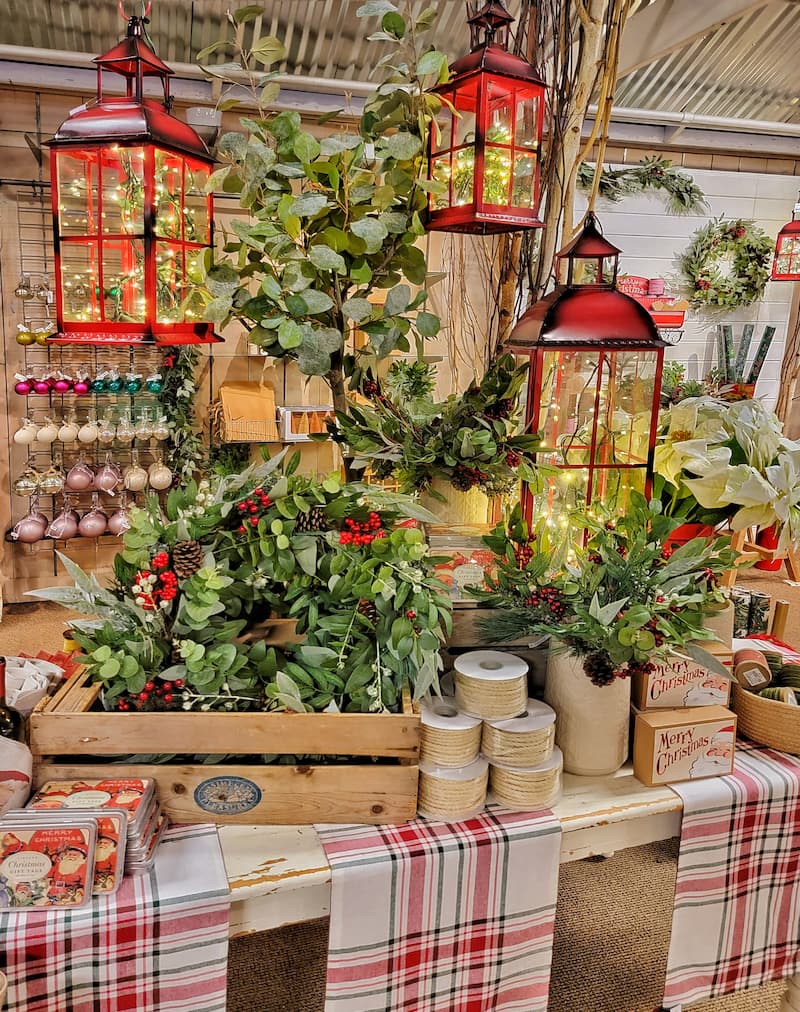  faux greenery and red lanterns with plaid runners on display at a store