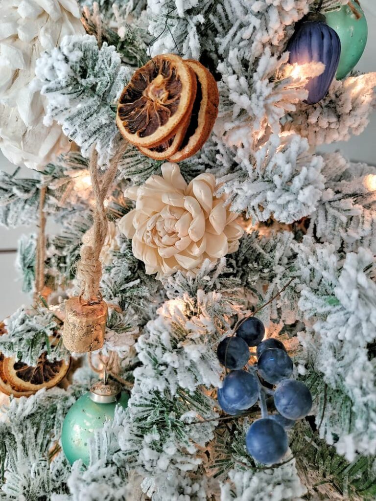 cream dried flower and dried oranges on flocked Christmas tree