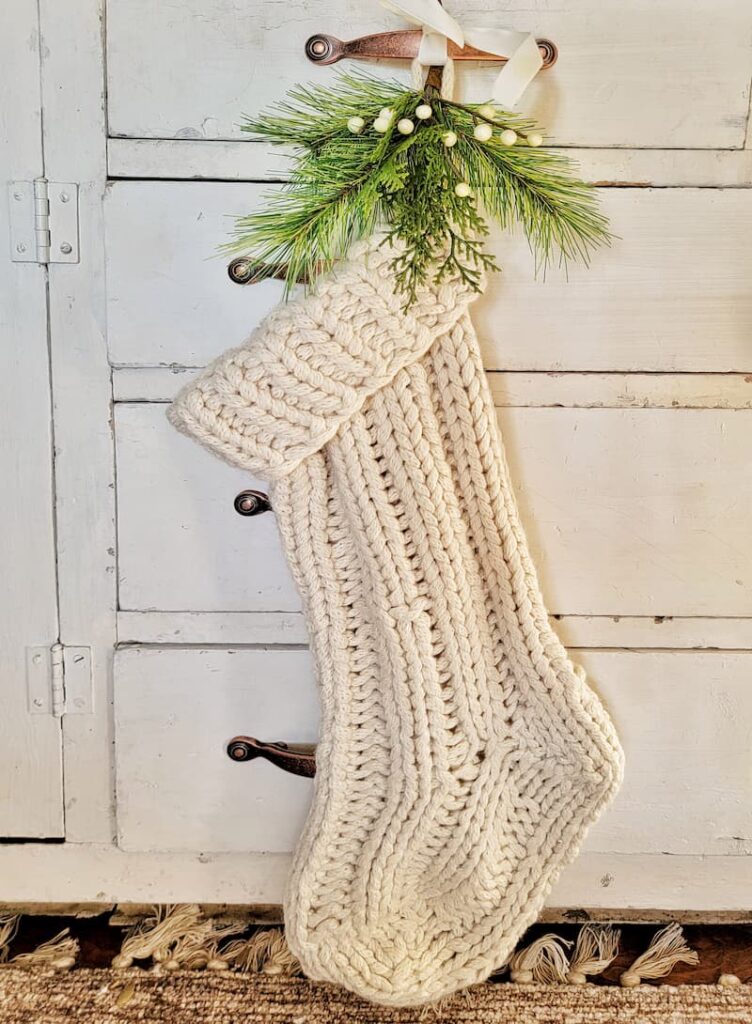 cream knit Christmas stocking and greenery