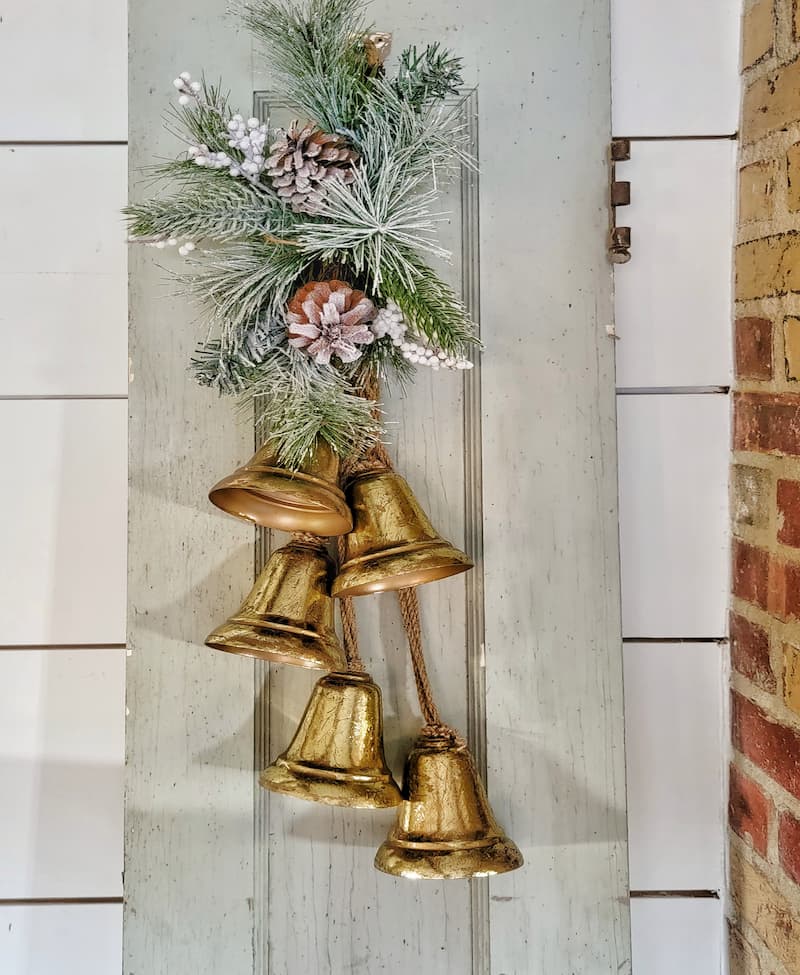 greenery and pinecones hanging on gold Christmas bells