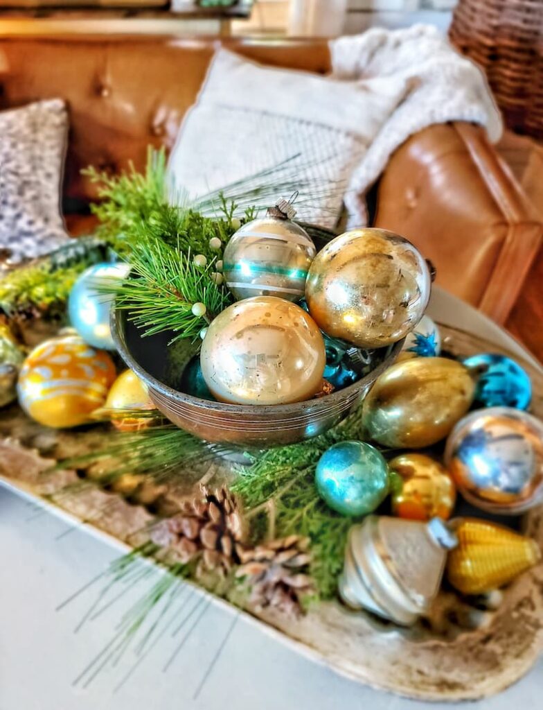 Christmas natural elements: vintage ornaments in silver bowl on tray with greenery and pinecones