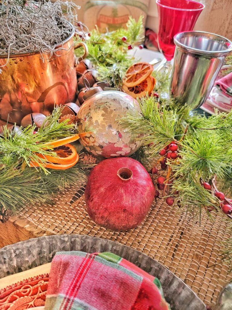 pomegranates, ornaments, and dried oranges with greenery on table