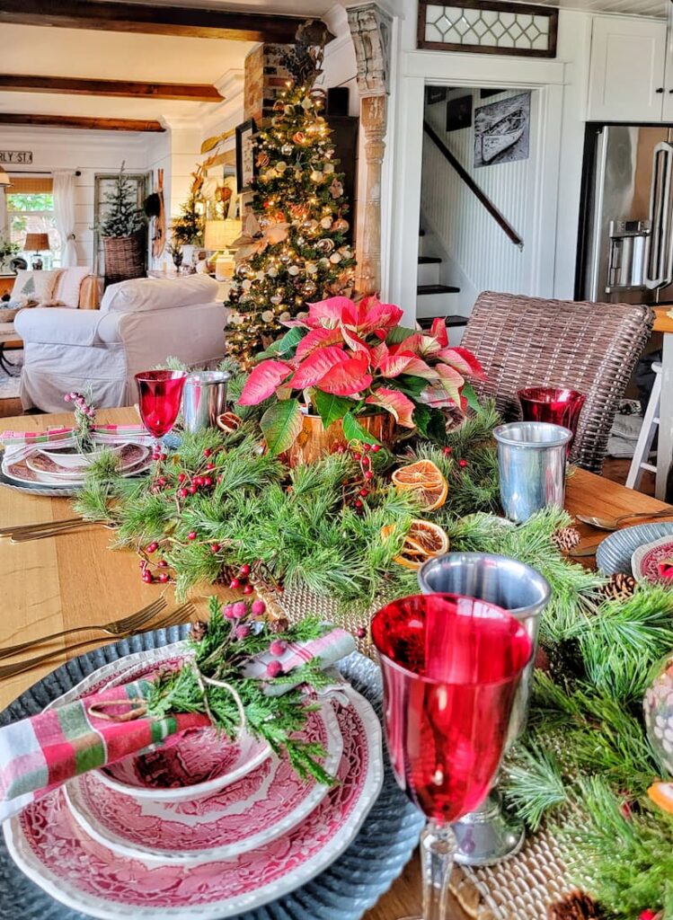Christmas tablescape with red and white dishes, red glasses, greenery and a poinsettia