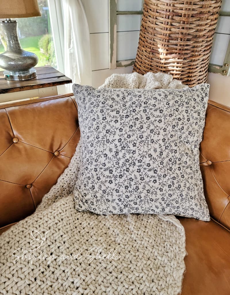 patterned gray and cream flower pillow and chunky knit throw blanket