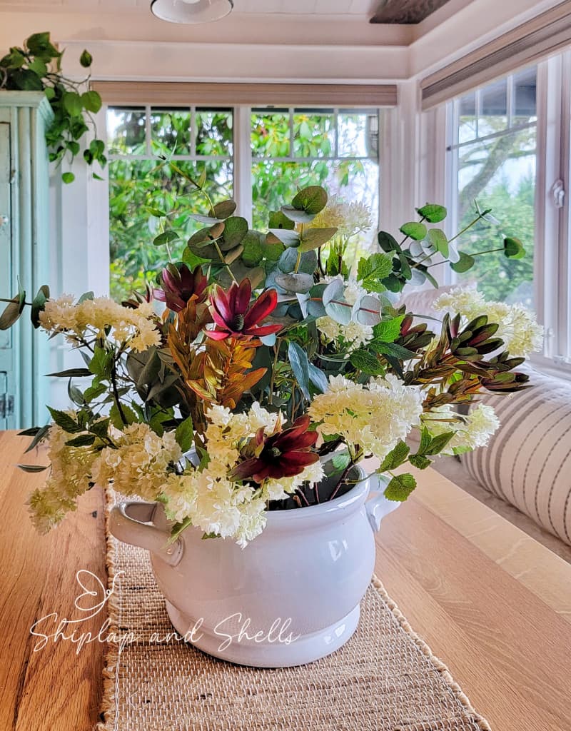 faux plants and flowers in white planter on kitchen table