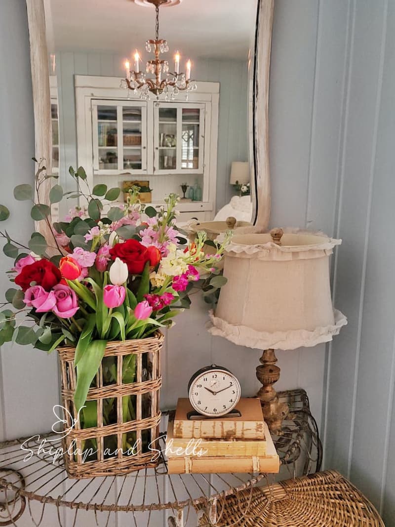 flower arrangement on a wire table with lamp and vintage books and clock