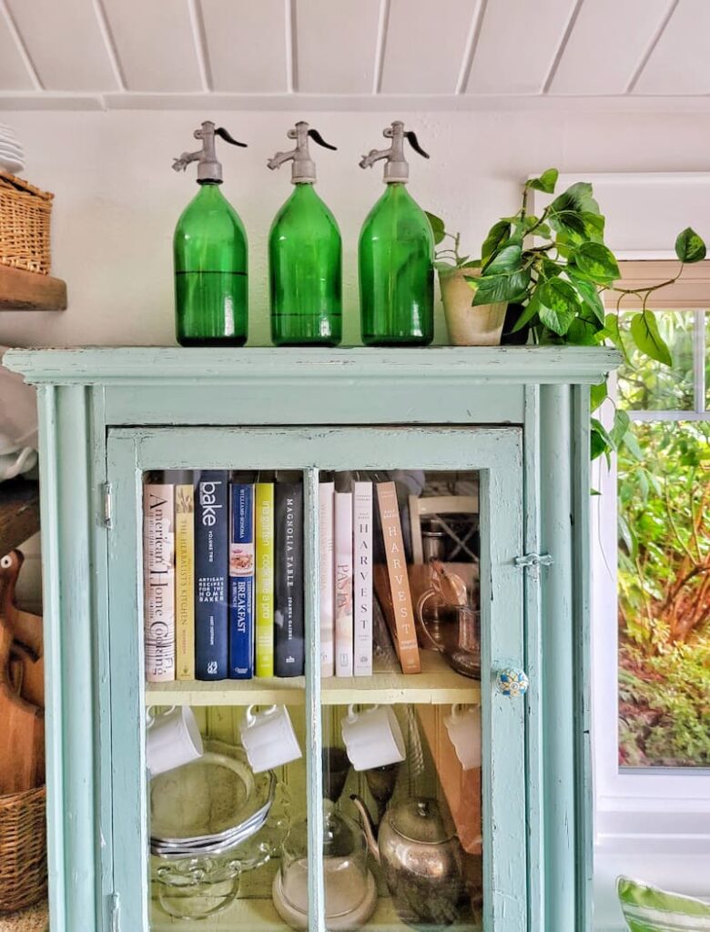 turquoise cabinet with green vintage seltzer bottles