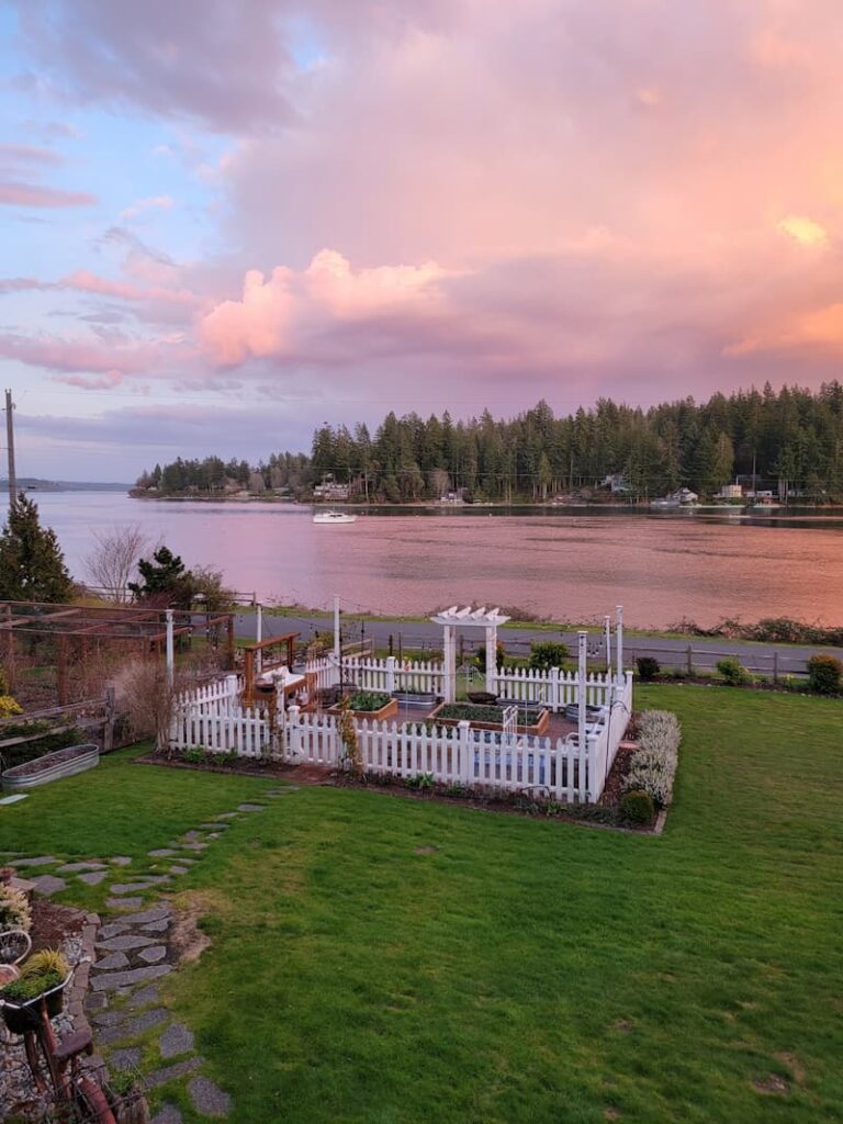 view of Puget Sound bay at sunset and white picket fence garden
