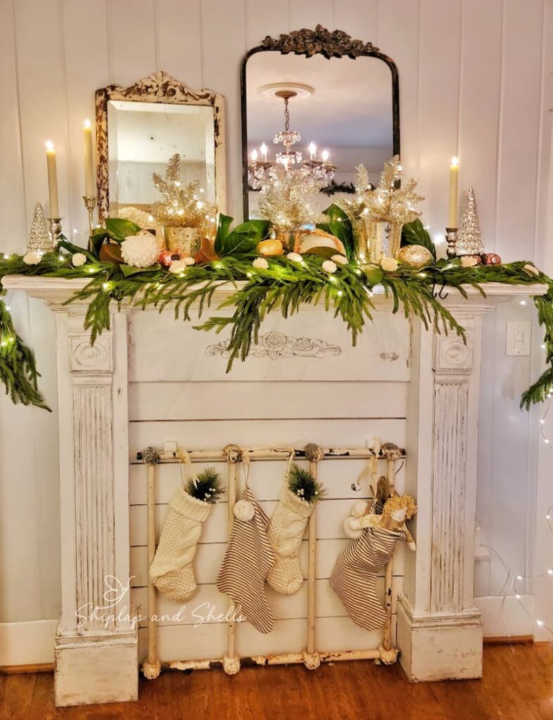fireplace mantel with garland, candles, ornaments and twinkle lights