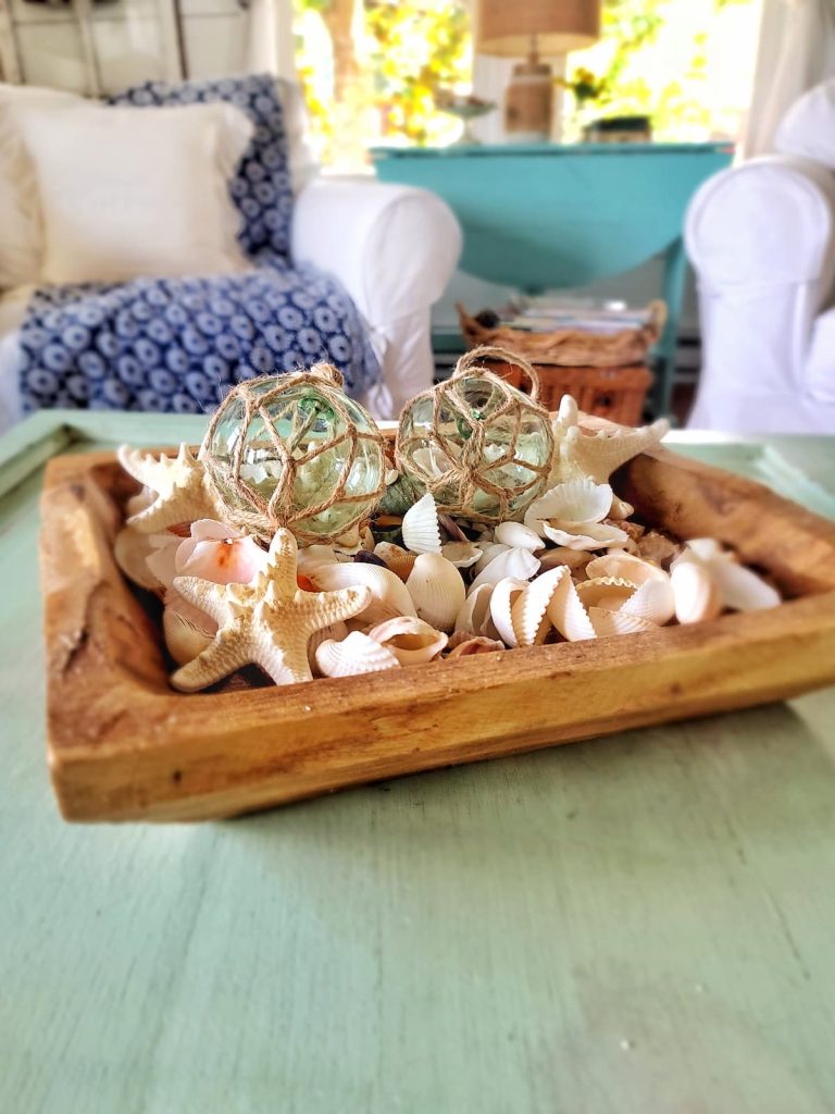 seashells and coastal glass balls in wood bowl